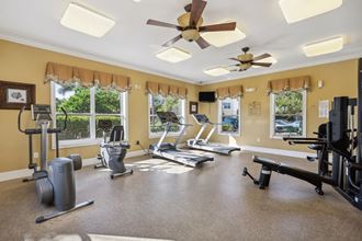 a home gym with exercise machines and a ceiling fan