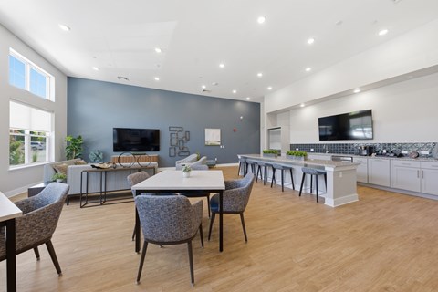 A modern kitchen and dining area with a large island and a TV mounted on the wall.
