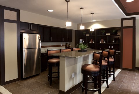 a kitchen with a bar and a stainless steel refrigerator