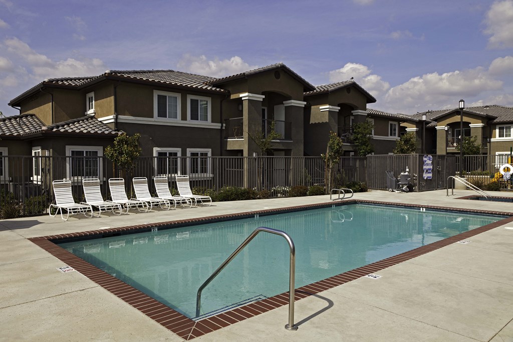 a swimming pool with chaise lounge chairs and a building in the background