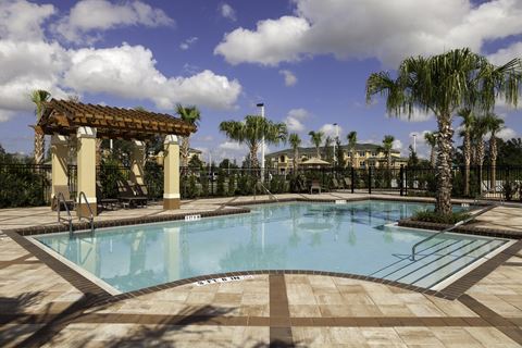 a large swimming pool with a gazebo and palm trees in the background