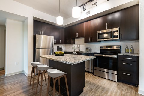 A kitchen with dark brown cabinets and a granite countertop.