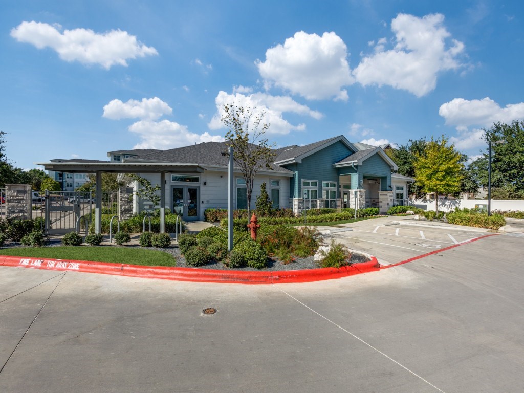 A parking lot with a red curb and a building in the background.
