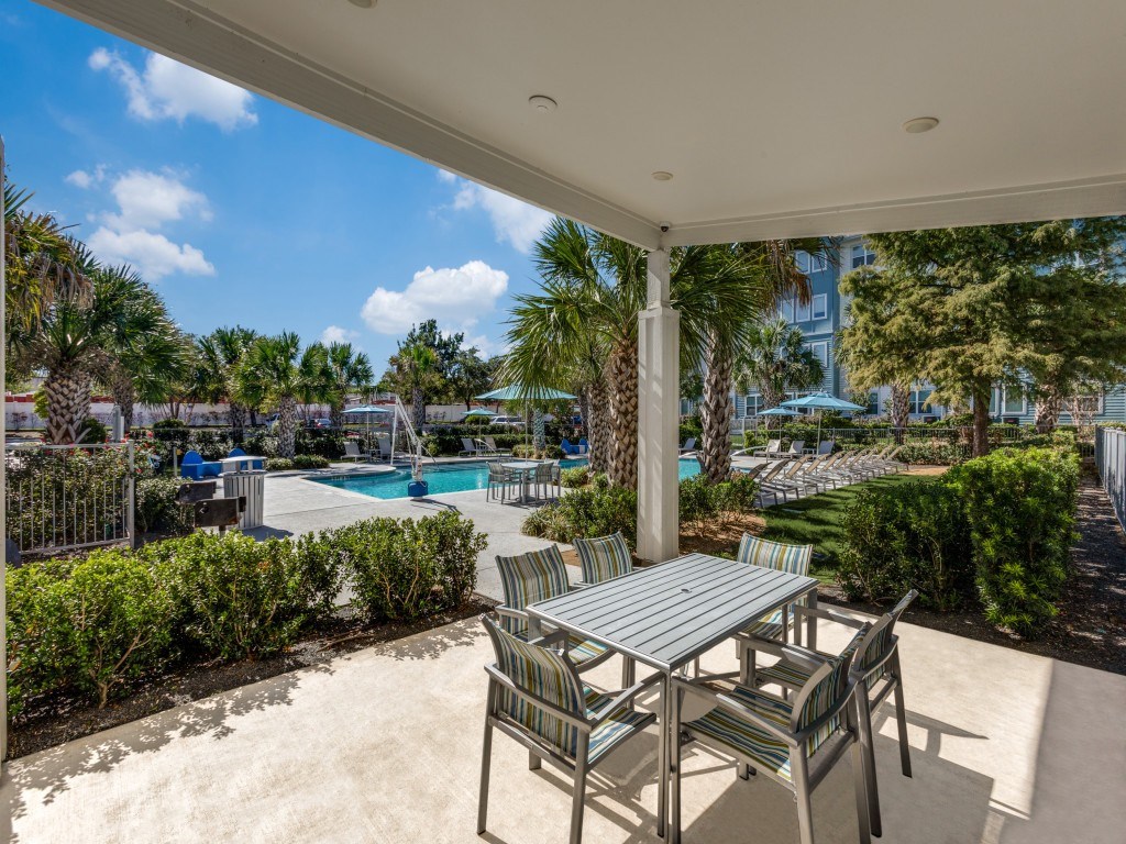 A patio with a table and chairs overlooking a pool.
