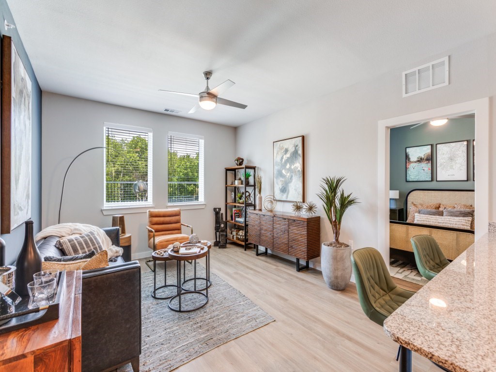 A living room with a brown sofa, a green chair, and a potted plant.