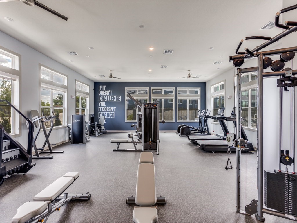A gym with a variety of equipment and a motivational wall quote.