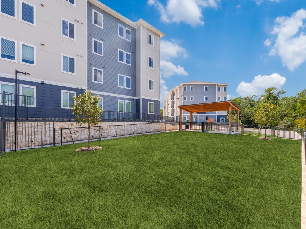 A large grassy area in front of a grey apartment building.