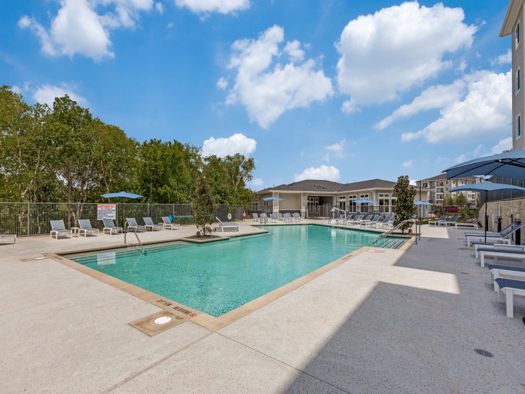 Resort style swimming pool with loungers and tables.