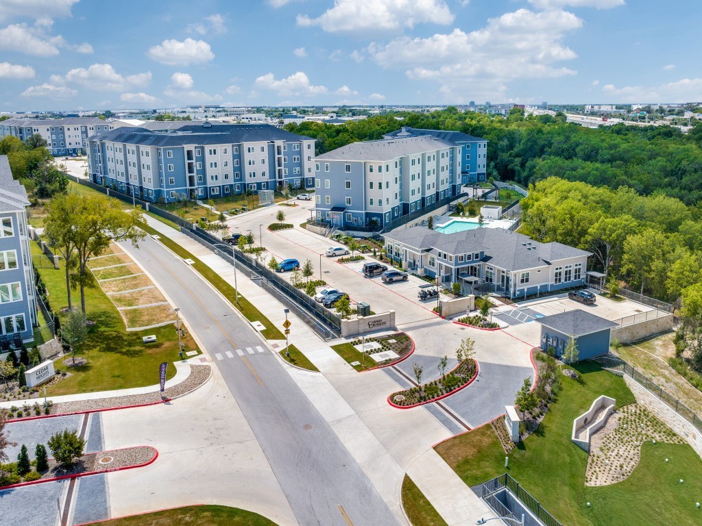 A large apartment complex with a parking lot in front.