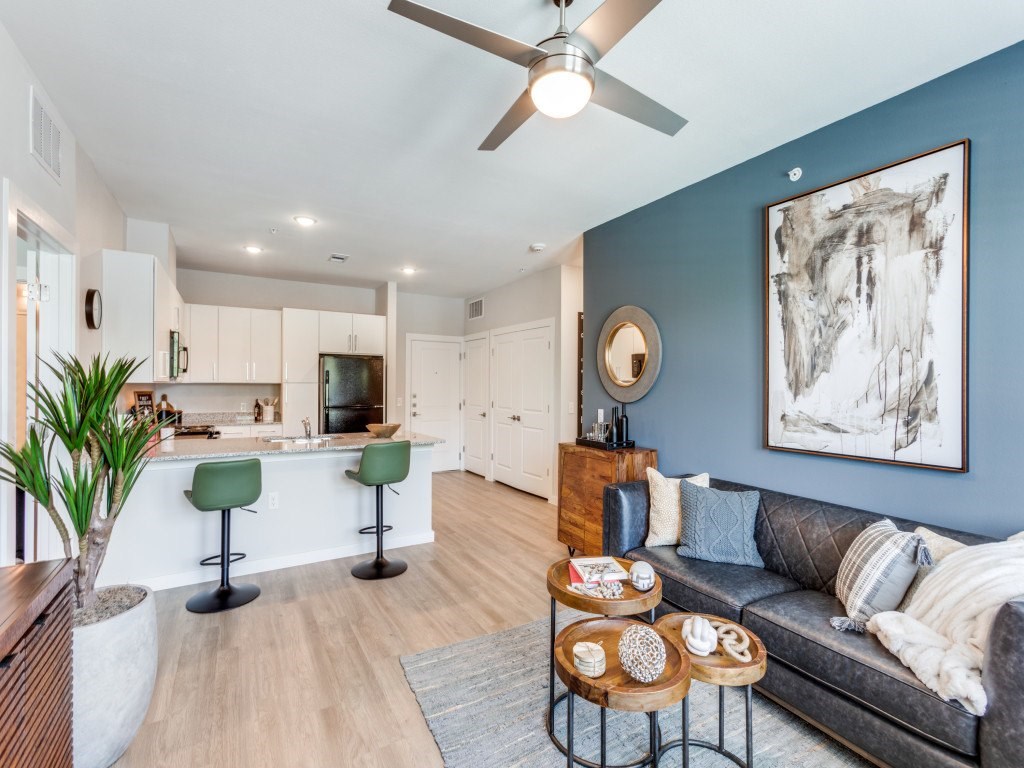 A living room with a grey couch, a coffee table, and a ceiling fan.