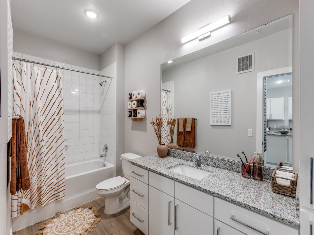 A bathroom with a white toilet, sink, and a shower with a brown towel.