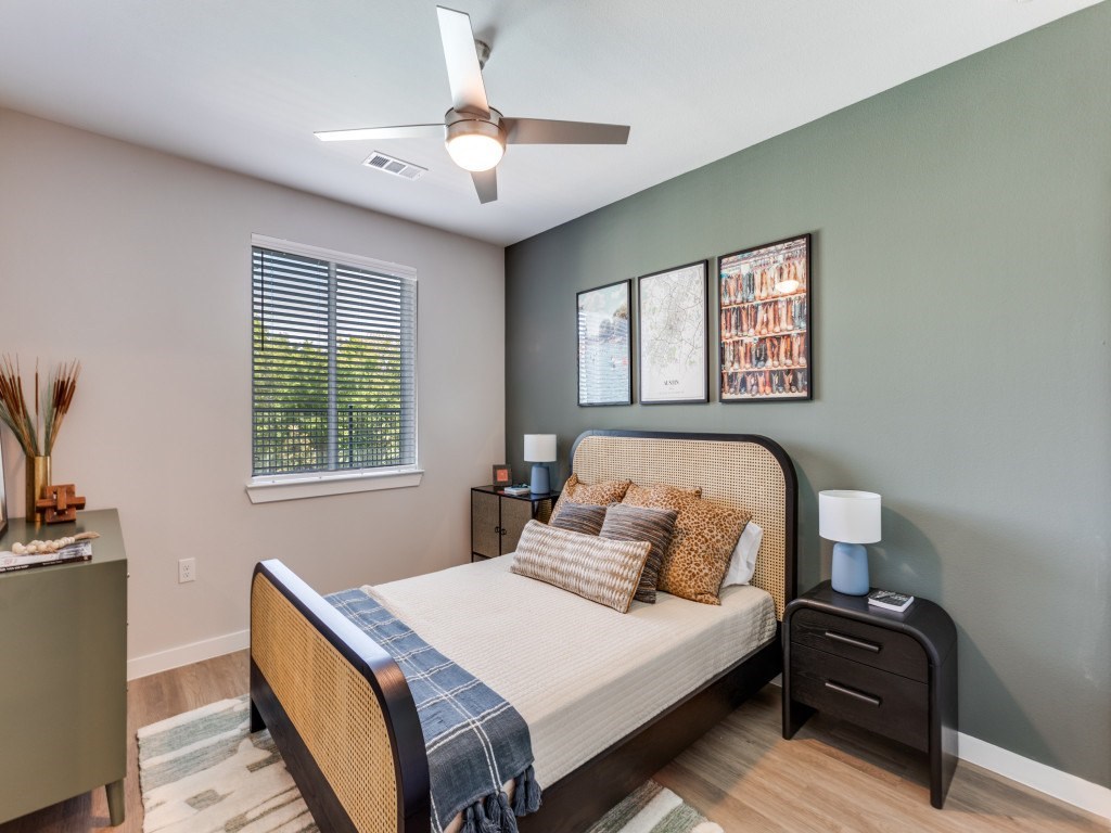 A bedroom with a bed, nightstands, and a ceiling fan.