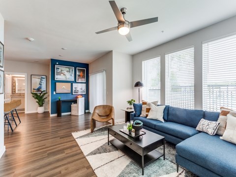 A living room with a blue couch and a wooden floor.