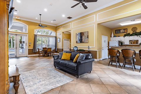 A living room with a black couch and a rug.