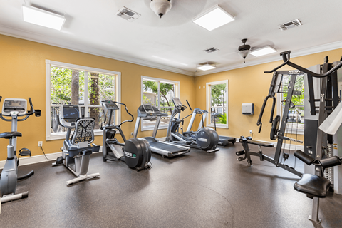A spacious gym with various exercise equipment and a ceiling fan.