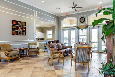 A living room with a brown sofa and wooden chairs.