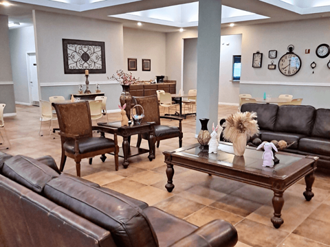 A living room with brown leather furniture and a large clock on the wall.