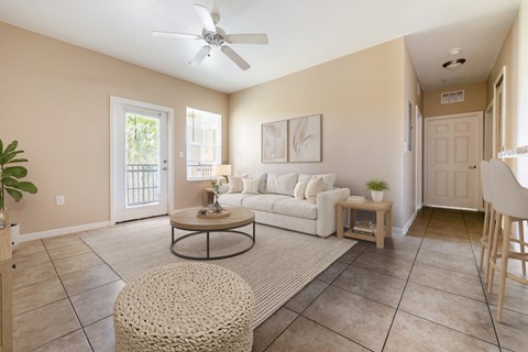 A living room with a white couch and a round ottoman.