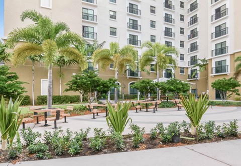 a courtyard with benches and trees in front of an apartment building