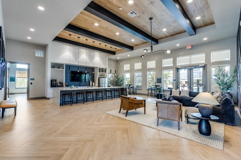 A spacious living room with a bar area and a kitchen in the background.