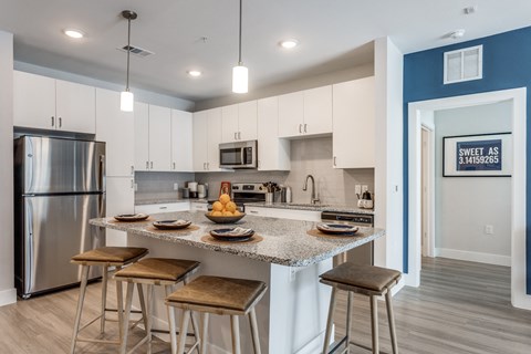 a kitchen with an island with bar stools and a stainless steel refrigerator