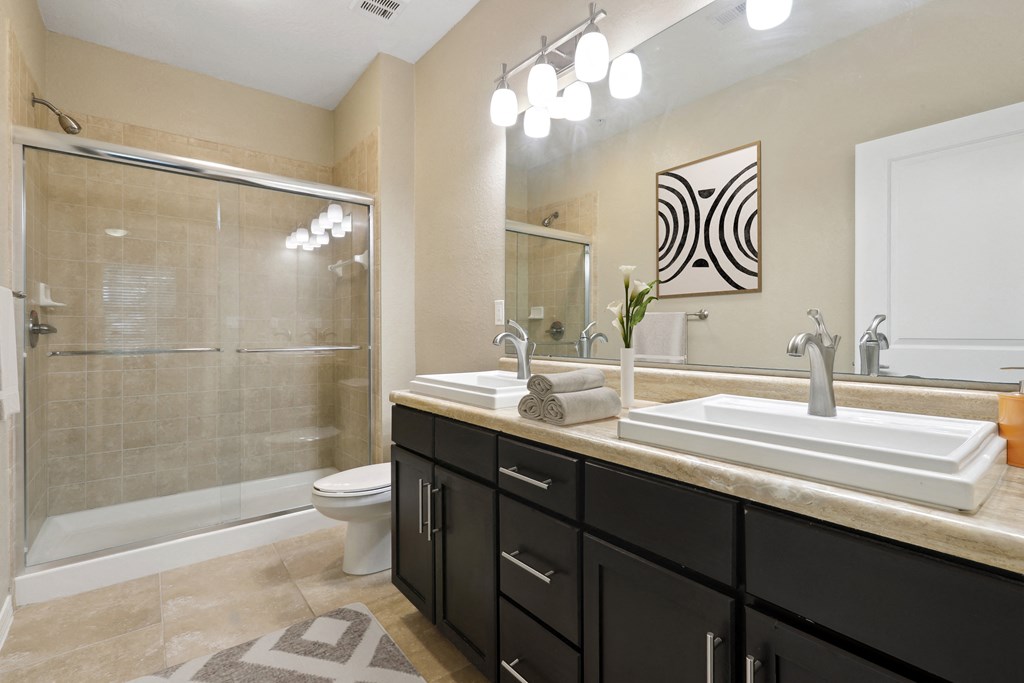 Bathroom with glass shower and double sink at The Amalfi Clearwater Apartments