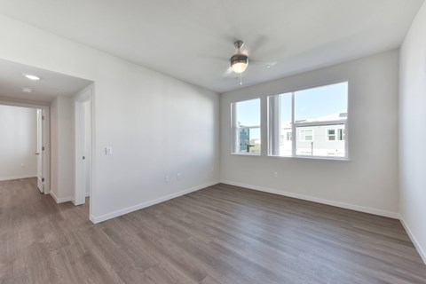 A spacious room with a ceiling fan and large windows.