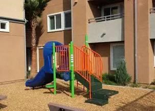 a playground with a blue slide in front of an apartment building