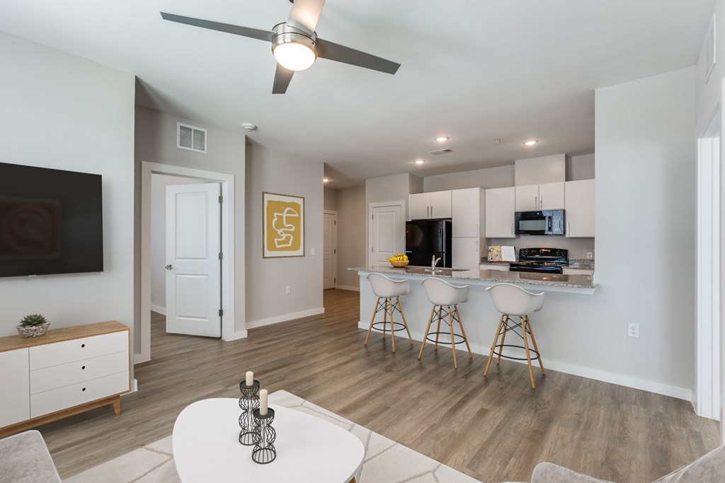 A living room with a white ceiling fan and a white dining table with four chairs.