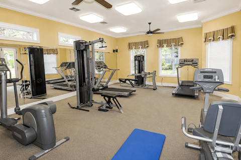 A spacious gym with a variety of equipment including treadmills, elliptical machines, and weight machines.