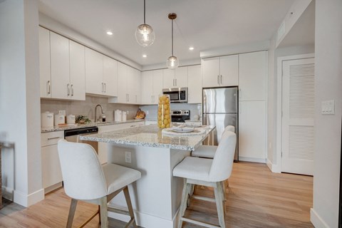 a kitchen with white cabinets and a marble counter top