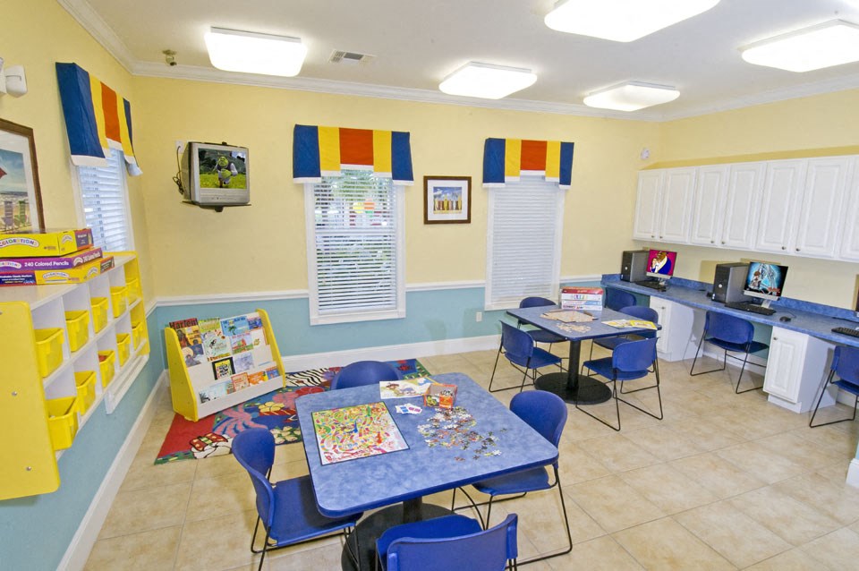 a play room with tables and chairs and a television