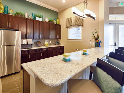 A kitchen with a granite counter top and a stainless steel refrigerator.
