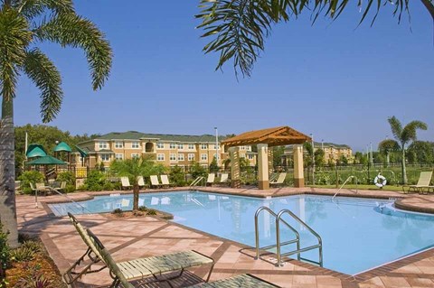 a swimming pool with chairs and a gazebo in front of a resort