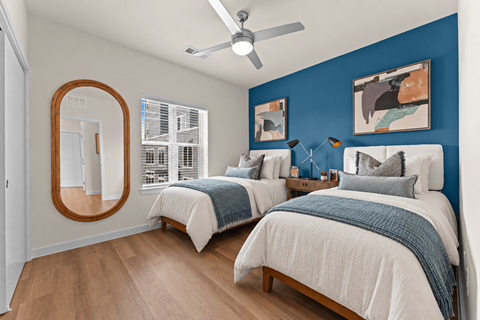 A bedroom with two beds and a ceiling fan.