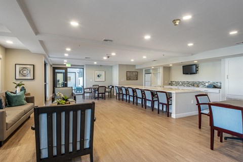 a community room with a kitchen and a bar with chairs