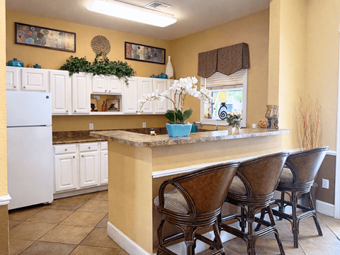 A kitchen with a white refrigerator and brown chairs.