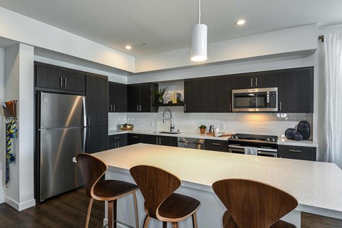 a kitchen with a large island and a stainless steel refrigerator