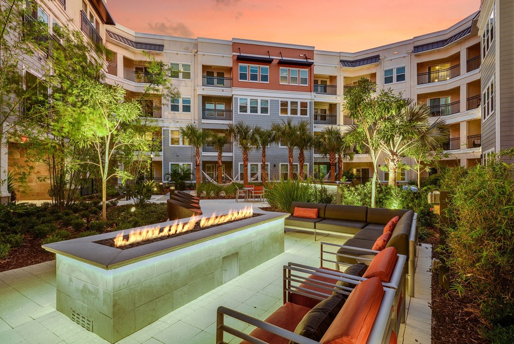 an outdoor lounge area with a fire pit in front of an apartment building  at Grady Square, Florida