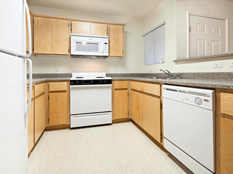 A kitchen with a white fridge, microwave, dishwasher and oven.