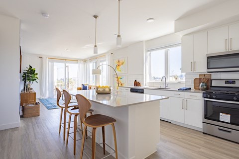 a kitchen with white cabinets and a large island with bar stools