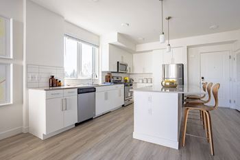 a kitchen with white cabinets and a large window