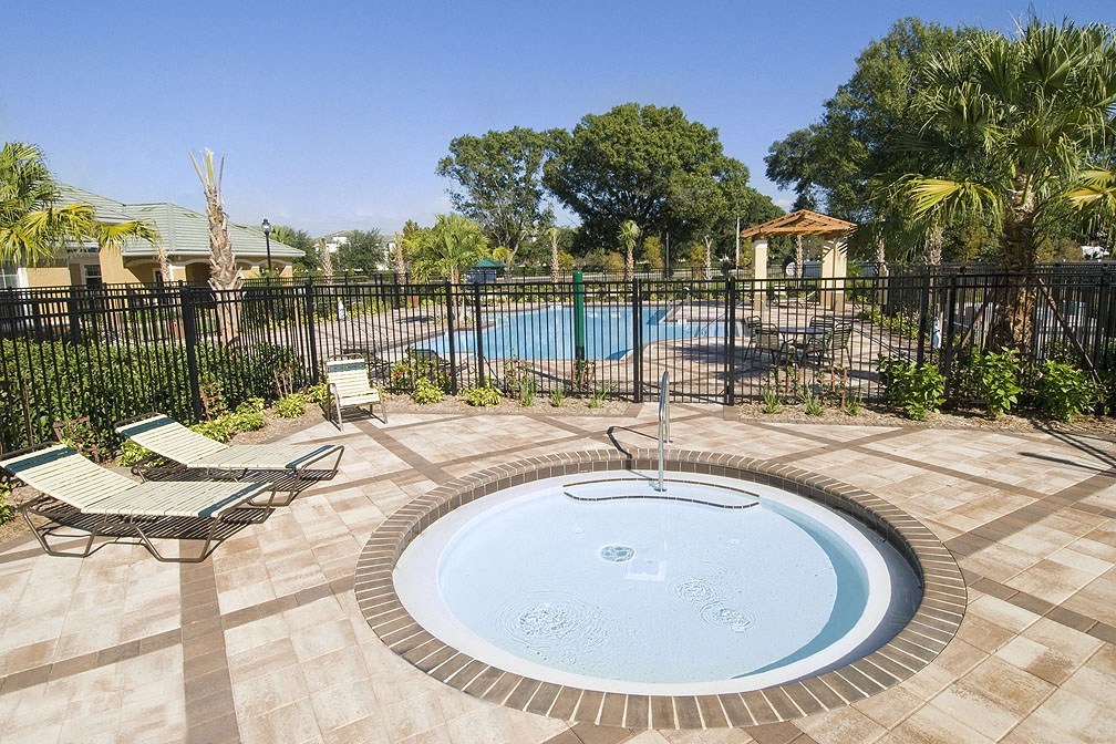 a jacuzzi in the backyard of a home with a black fence