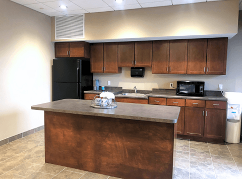 A kitchen with a black refrigerator and brown cabinets.