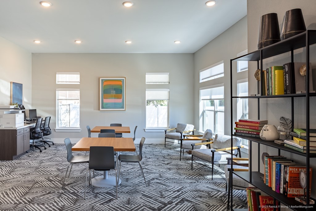 A room with a long table and chairs, a bookshelf, and a painting on the wall.