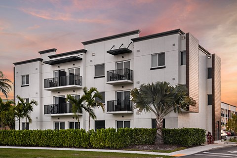 a white apartment building with palm trees in front of it