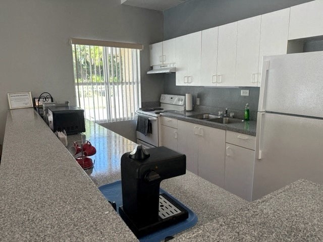 a kitchen with a white refrigerator freezer next to a stove top oven