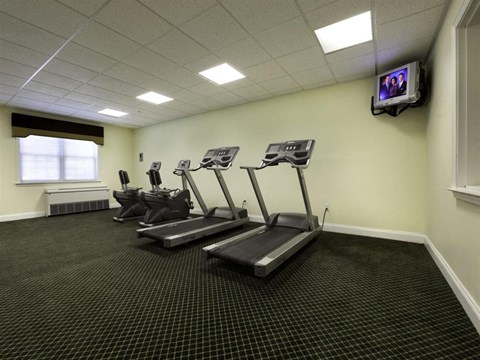 a gym with cardio machines and a tv