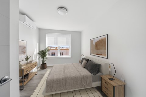 A bedroom with a bed, nightstand, and a window overlooking a cityscape.