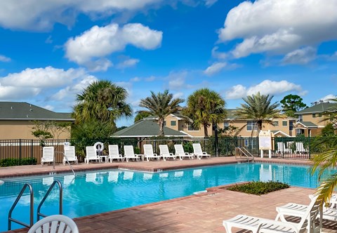 a swimming pool with chairs and palm trees